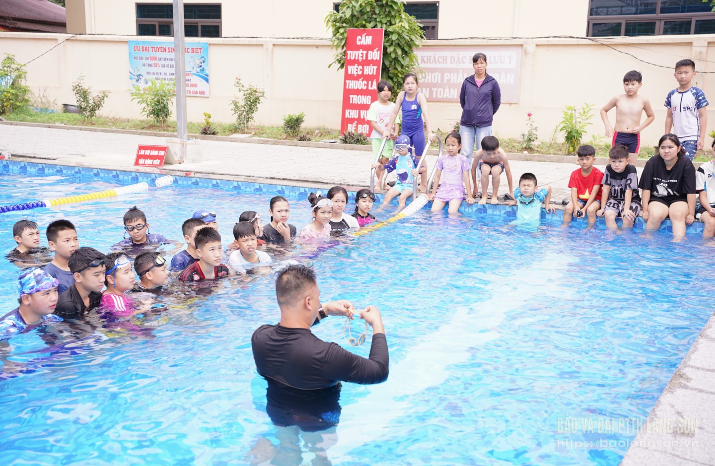 Huấn luyện viên hướng dẫn kỹ năng bơi lội cho các em học sinh